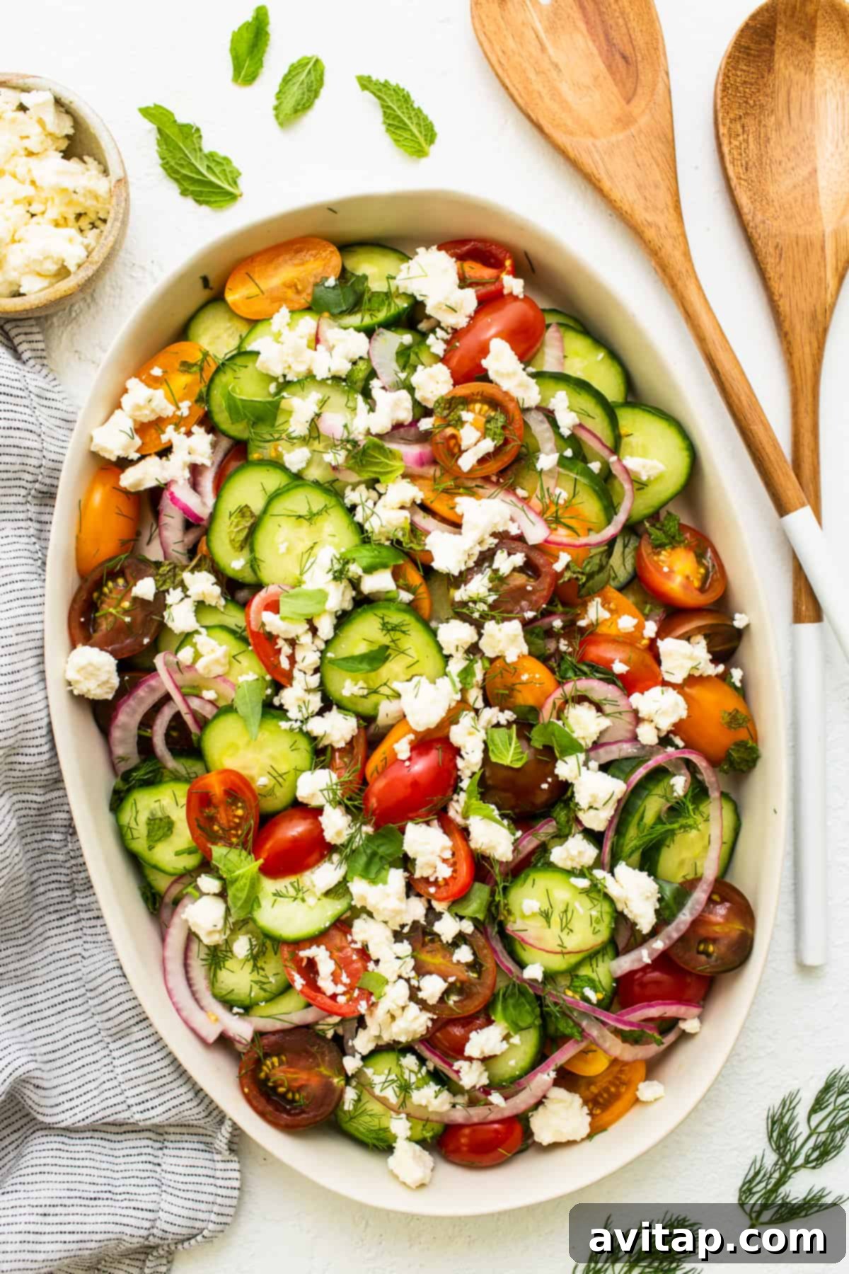 Vibrant Herb Cucumber Tomato Medley 2 A vibrant cucumber tomato salad served in an elegant platter, garnished with fresh herbs and feta.
