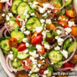 Vibrant Herb Cucumber Tomato Medley 7 A close-up shot of a refreshing cucumber tomato salad beautifully topped with crumbled feta cheese, ready to be served and enjoyed.
