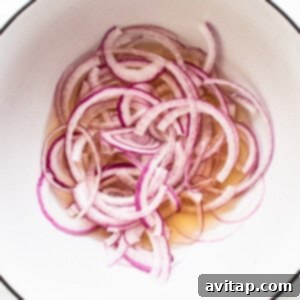 Vibrant Herb Cucumber Tomato Medley 8 Thinly sliced red onions soaking in a bowl with vinegar mixture, beginning the quick pickling process and infusing flavor.
