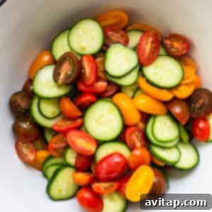 Vibrant Herb Cucumber Tomato Medley 9 Salted cherry tomatoes and sliced cucumbers resting in a colander, allowing excess moisture to drain into a bowl below.