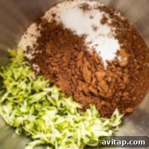 A bowl of dry ingredients with zucchini and chocolate in it.