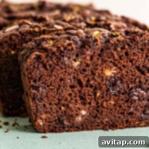 A slice of chocolate zucchini bread on a green cutting board.
