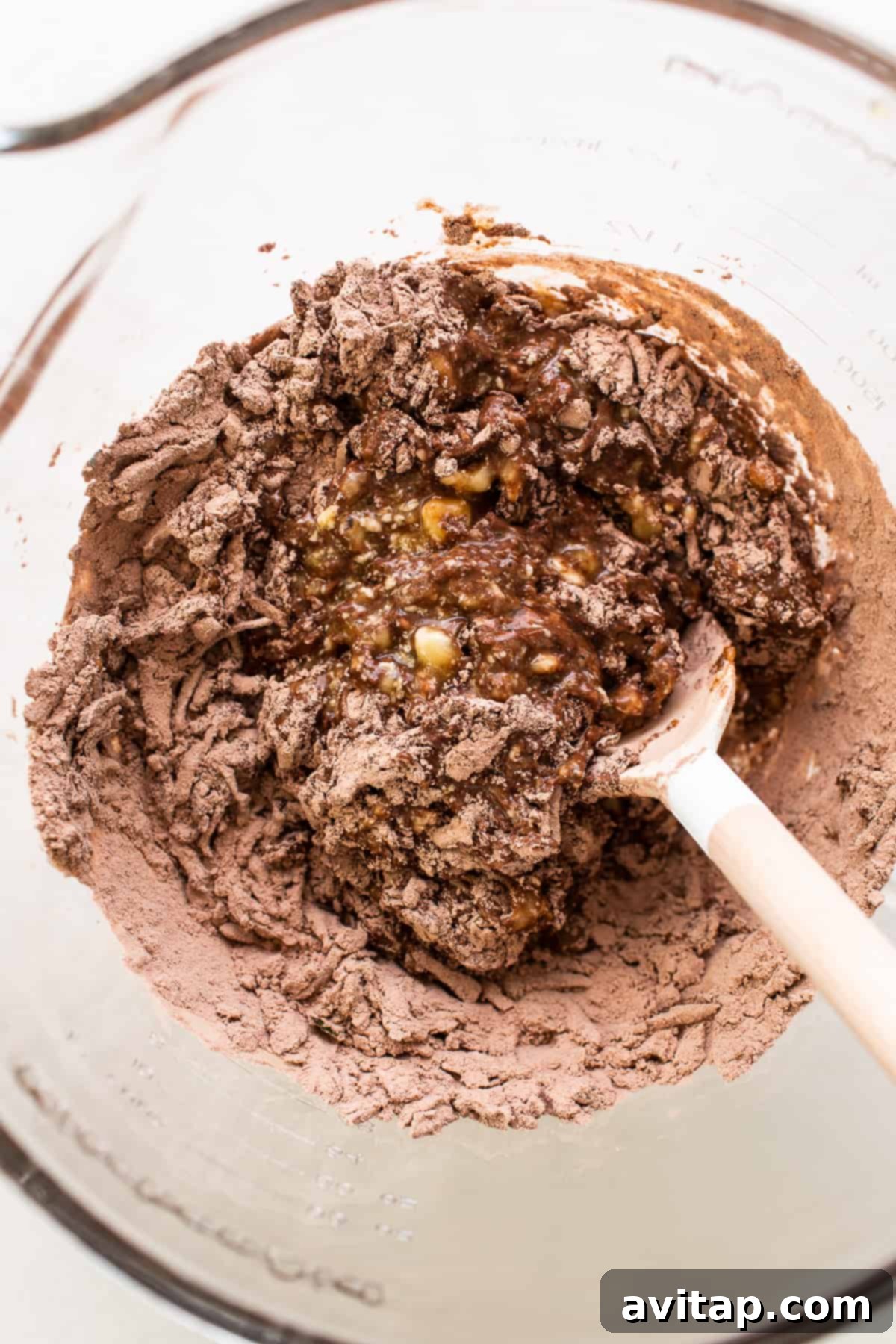 Wet and dry ingredients for chocolate zucchini bread combined in a bowl, ready for mixing.