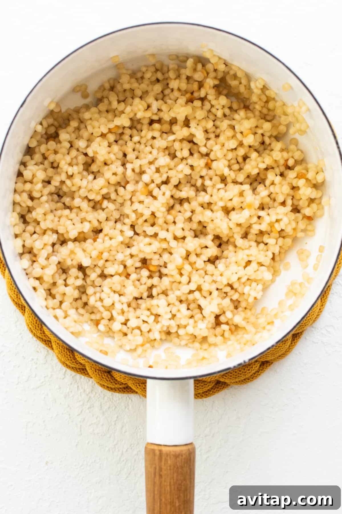 Preparing the base for our Black Bean Couscous Salad: Israeli couscous in a pot, which will provide a hearty and satisfying texture. Israeli couscous cooking in a pot on a stovetop, ready for a delicious salad preparation.