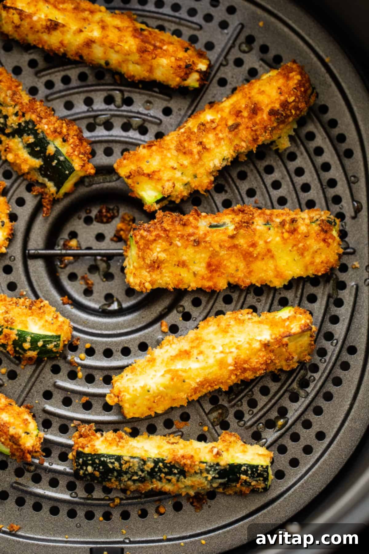 Air fryer zucchini fries arranged neatly inside an air fryer basket.