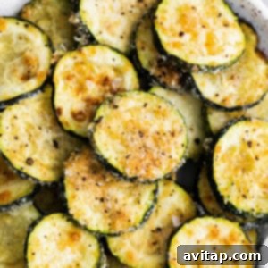 Stacked zucchini rounds on a plate, seasoned with garlic and Parmesan.