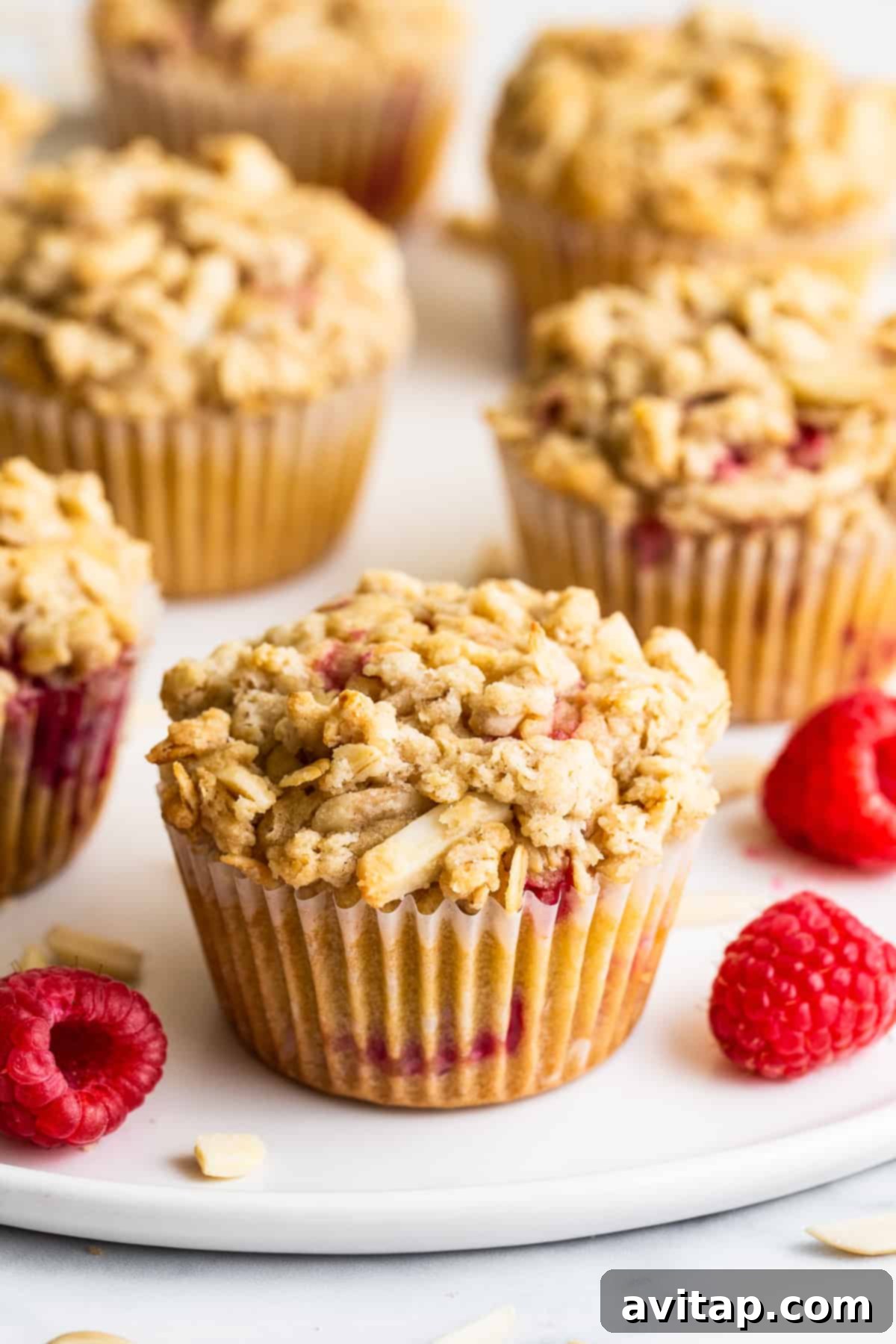 Perfectly baked fluffy raspberry muffins with golden streusel topping on a kitchen counter, ready to be enjoyed as a delightful breakfast or snack.