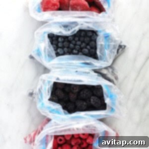 Three bags of various frozen berries (raspberries, blueberries, and mixed berries), illustrating how to store them for future use and retain freshness.