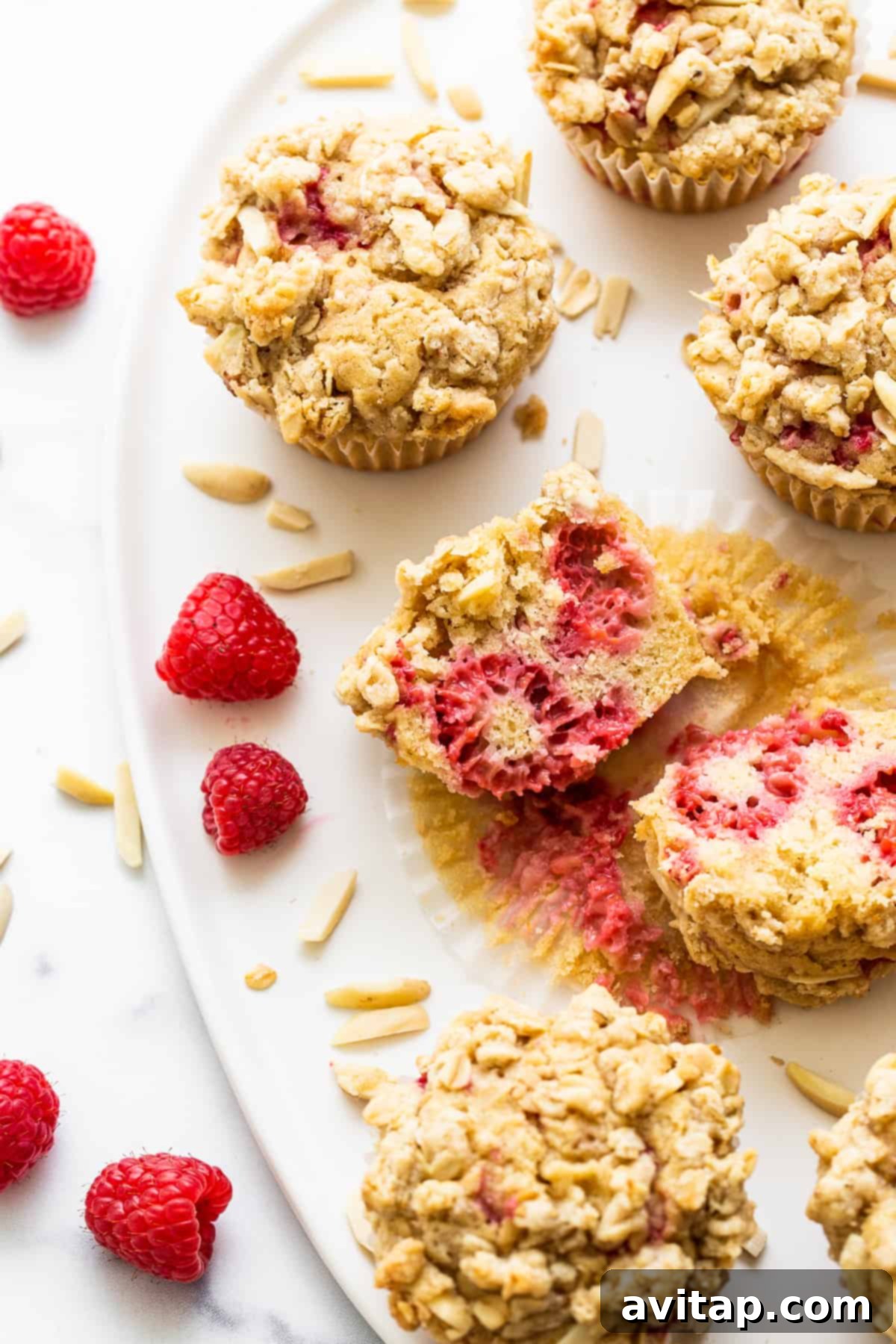 A perfectly sliced raspberry muffin reveals its fluffy, moist interior studded with juicy raspberries and a golden streusel top, ready to be enjoyed.