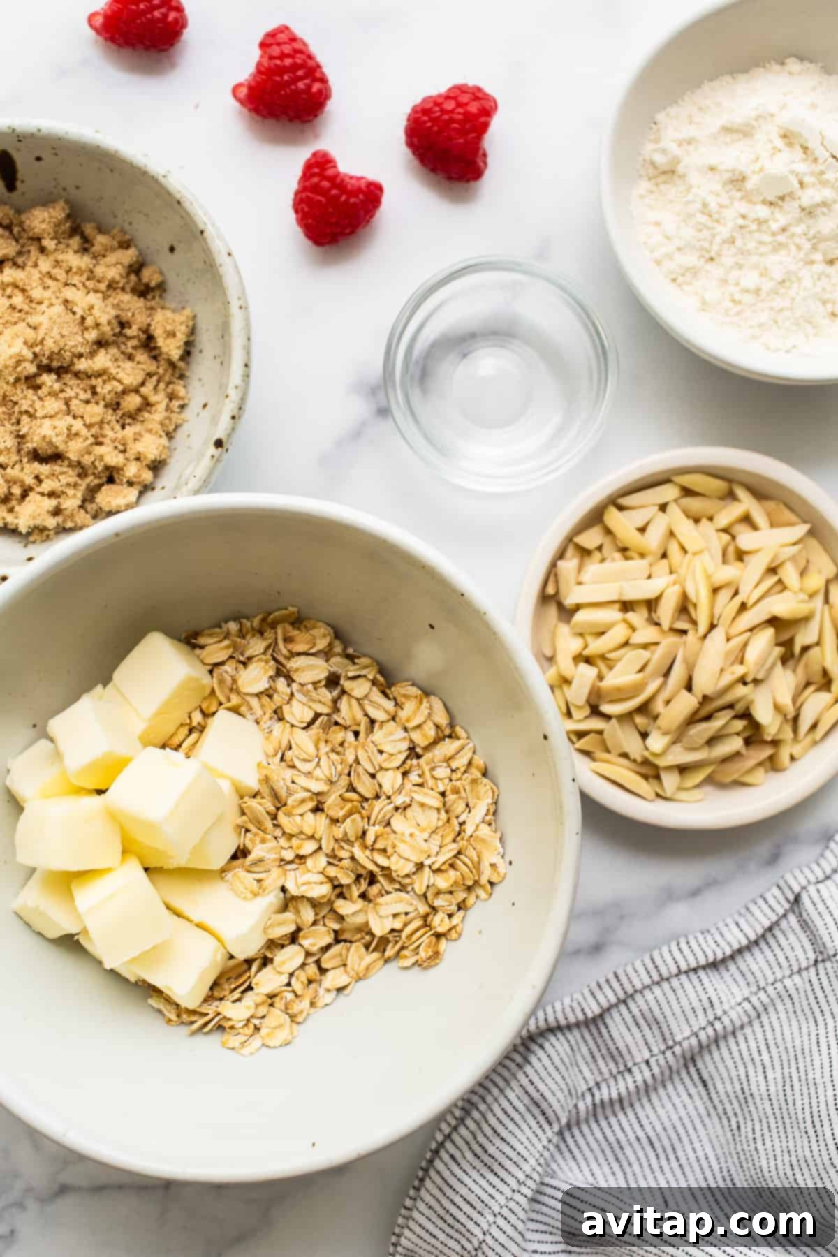 Carefully arranged ingredients for baking delicious raspberry muffins laid out on a clean kitchen counter, showcasing fresh raspberries, flour, eggs, butter, and lemon.