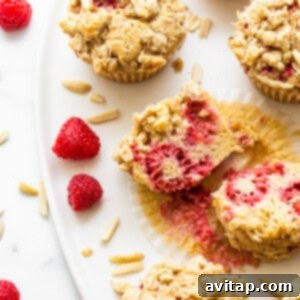 A beautifully baked raspberry muffin, sliced open to show its fluffy interior and fruit distribution.