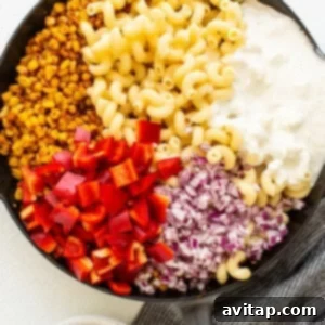 Fiesta Corn Pasta Salad 11 Pasta, corn, and vegetables being tossed with a creamy dressing in a large skillet.