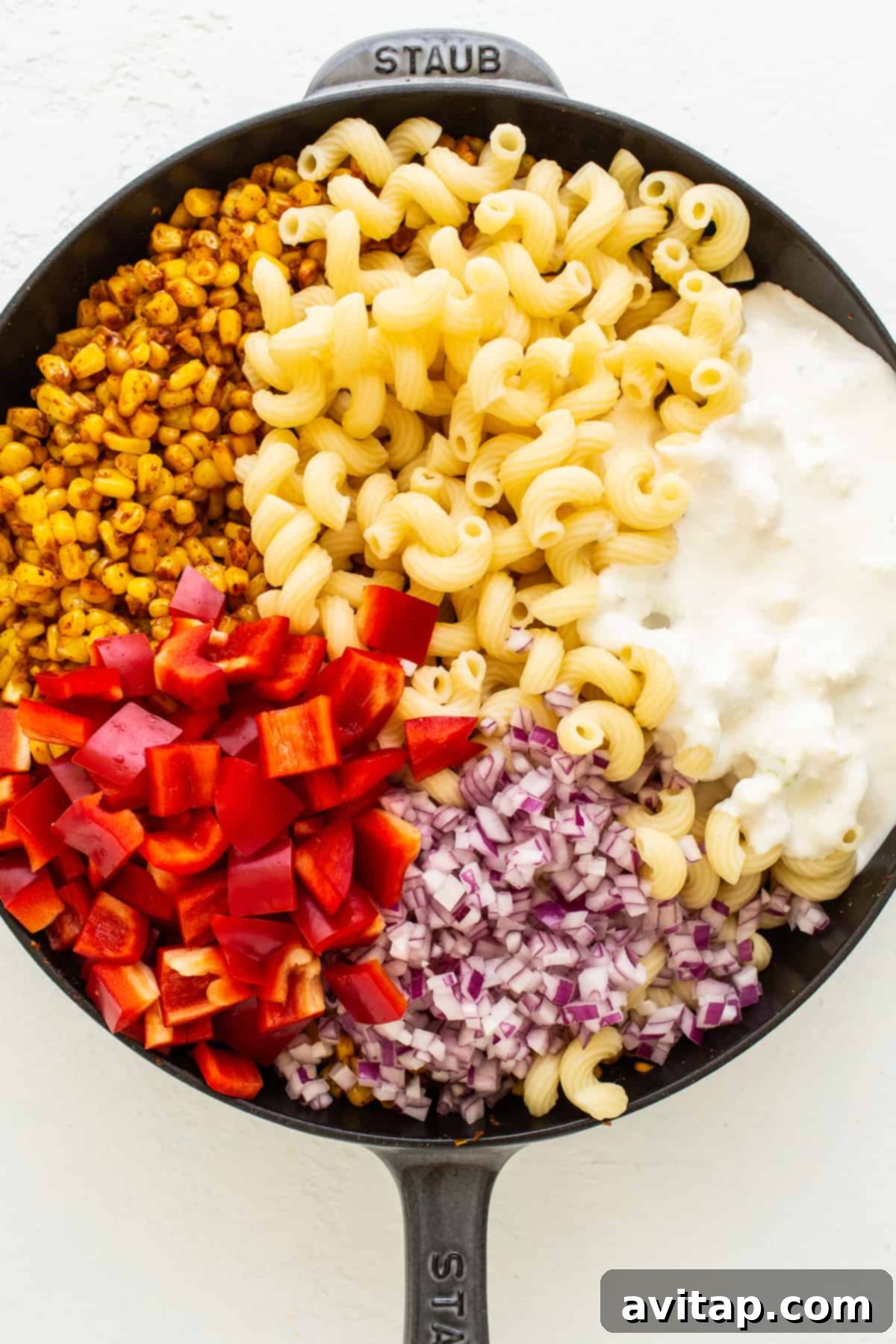 Fiesta Corn Pasta Salad 5 A cast iron skillet filled with seasoned corn, bell peppers, and red onion, ready to be tossed with pasta and dressing.