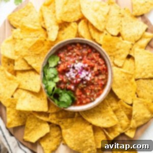 Nachos with homemade salsa beautifully arranged on a wooden cutting board, inviting for a delicious snack.