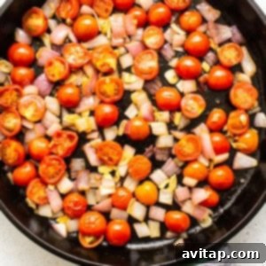Tomatoes and onions sautéing in a skillet, creating a flavorful base.