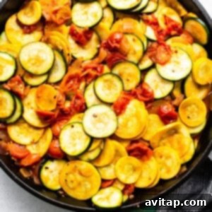 Zucchini and yellow squash cooking in a skillet with the vibrant sauce.