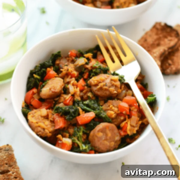 A bowl of kale and sausage with bread and a gold fork.