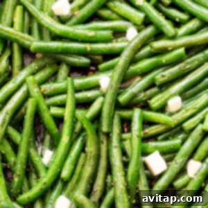 Cooked green beans in a pan, finished with butter, lemon, and pepper.