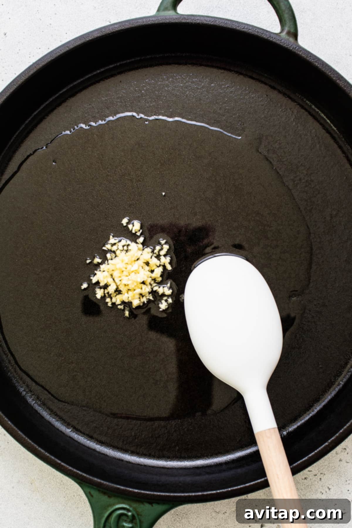 Minced garlic sizzling in olive oil in a hot skillet, releasing its aromatic fragrance.