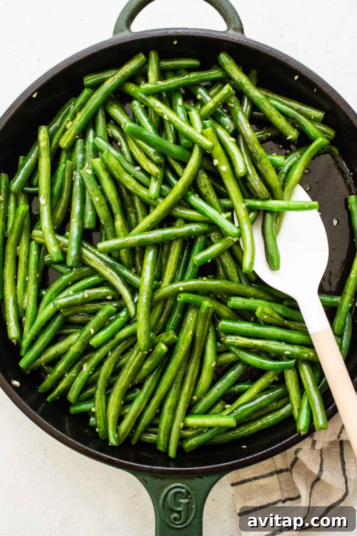 Sautéing green beans in a cast iron pan Green beans being sautéed with garlic in a cast iron pan, turning vibrant green.