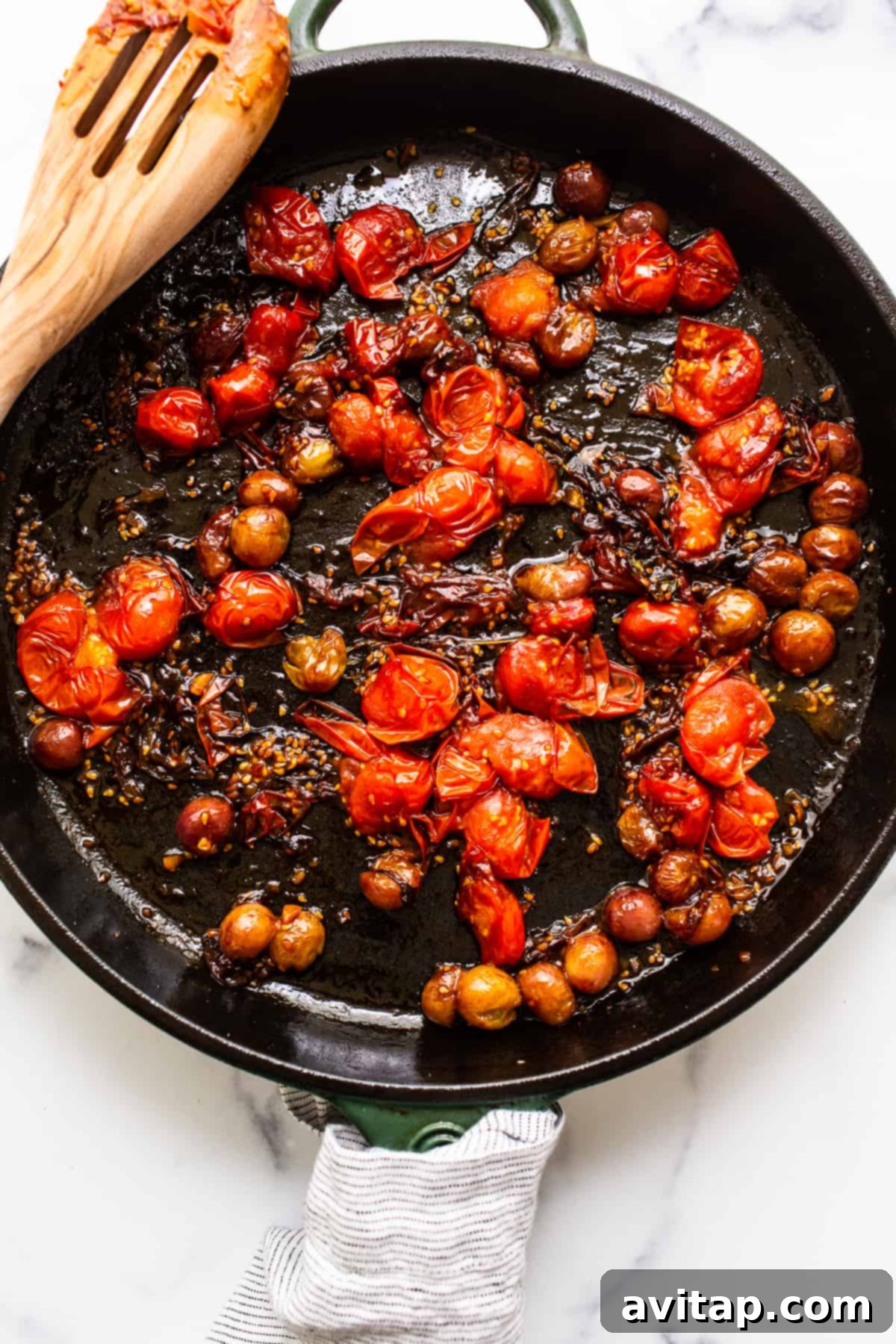 Cooked down cherry tomatoes and grapes simmering in a cast iron skillet, forming a rich sauce.