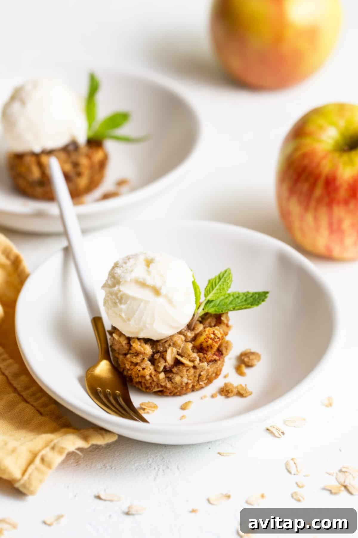 Golden brown mini apple crisp in a bowl, topped with melting vanilla ice cream, ready to be enjoyed as a perfect fall dessert.