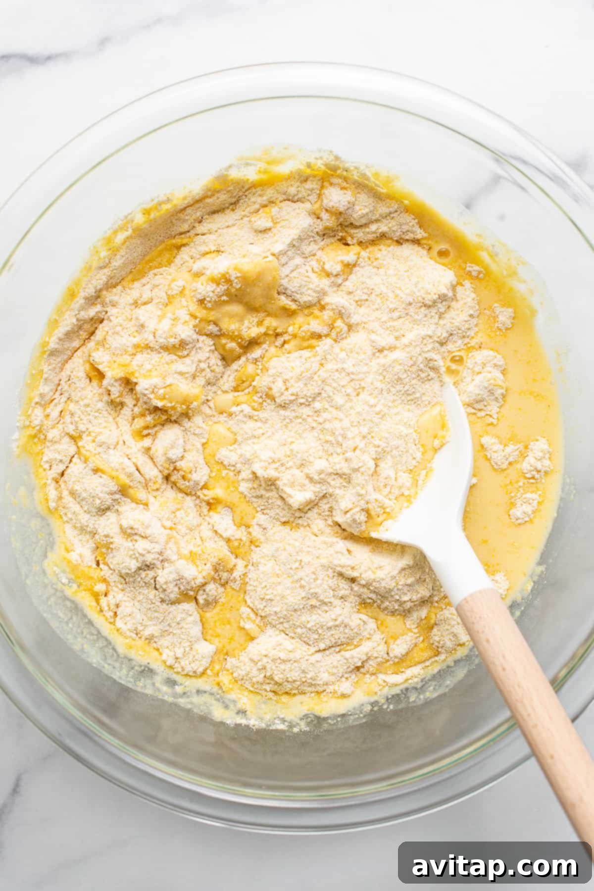 Cornbread mix in a mixing bowl, showing its grainy texture, ready to be combined with wet ingredients.