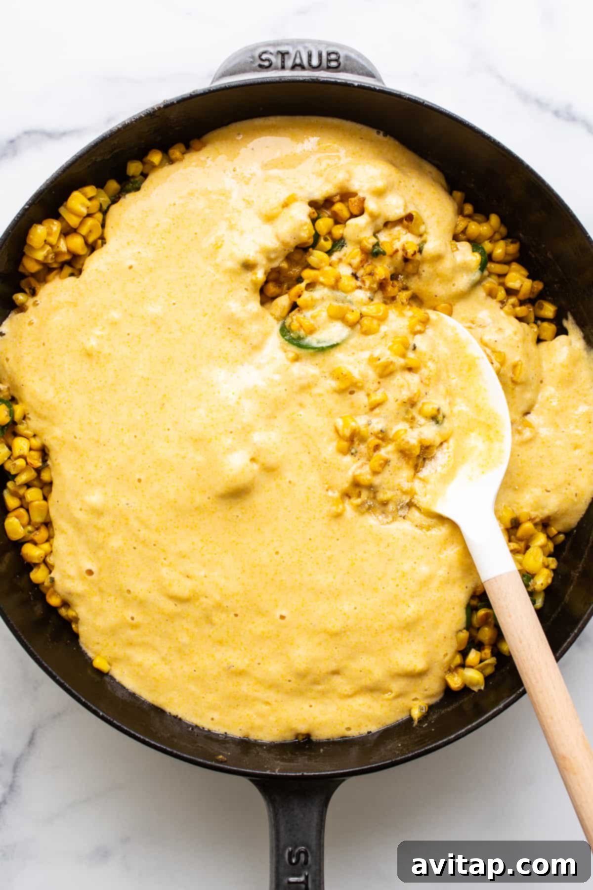 The corn pudding mixture, perfectly combined with jalapeño slices on top, just before baking in the cast iron skillet.