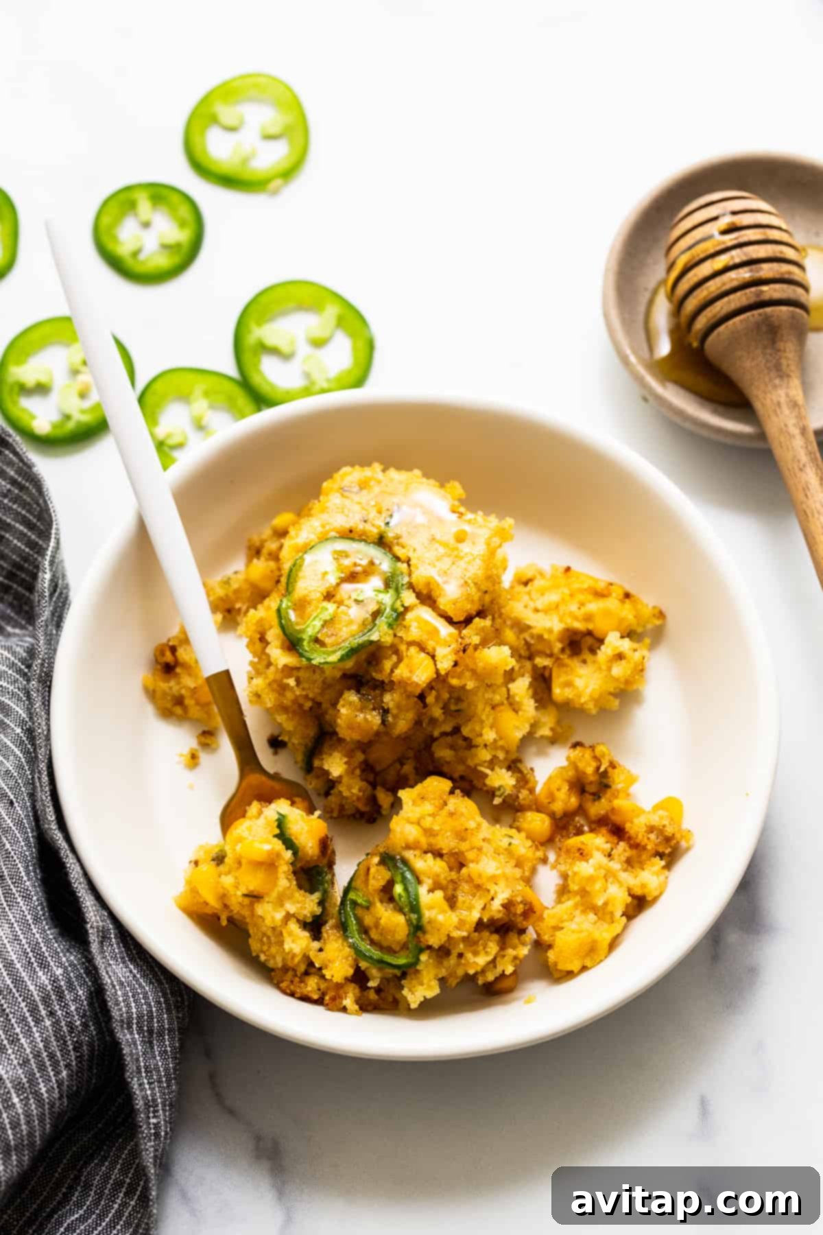 A delicious single serving of jalapeño corn pudding in a rustic bowl, with a fork ready to enjoy its sweet and spicy flavors.