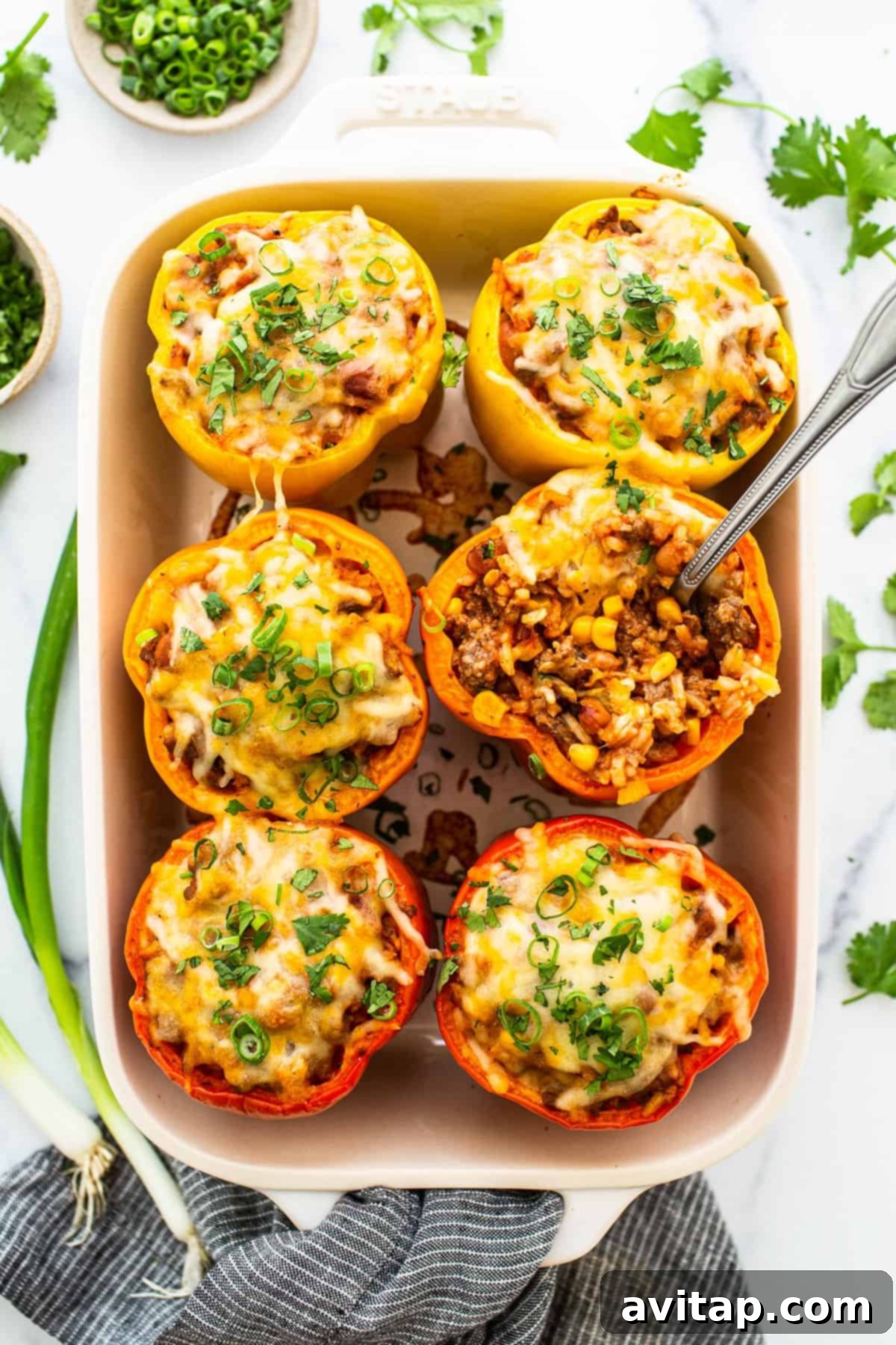Easy stuffed peppers in a casserole dish topped with shredded cheese.