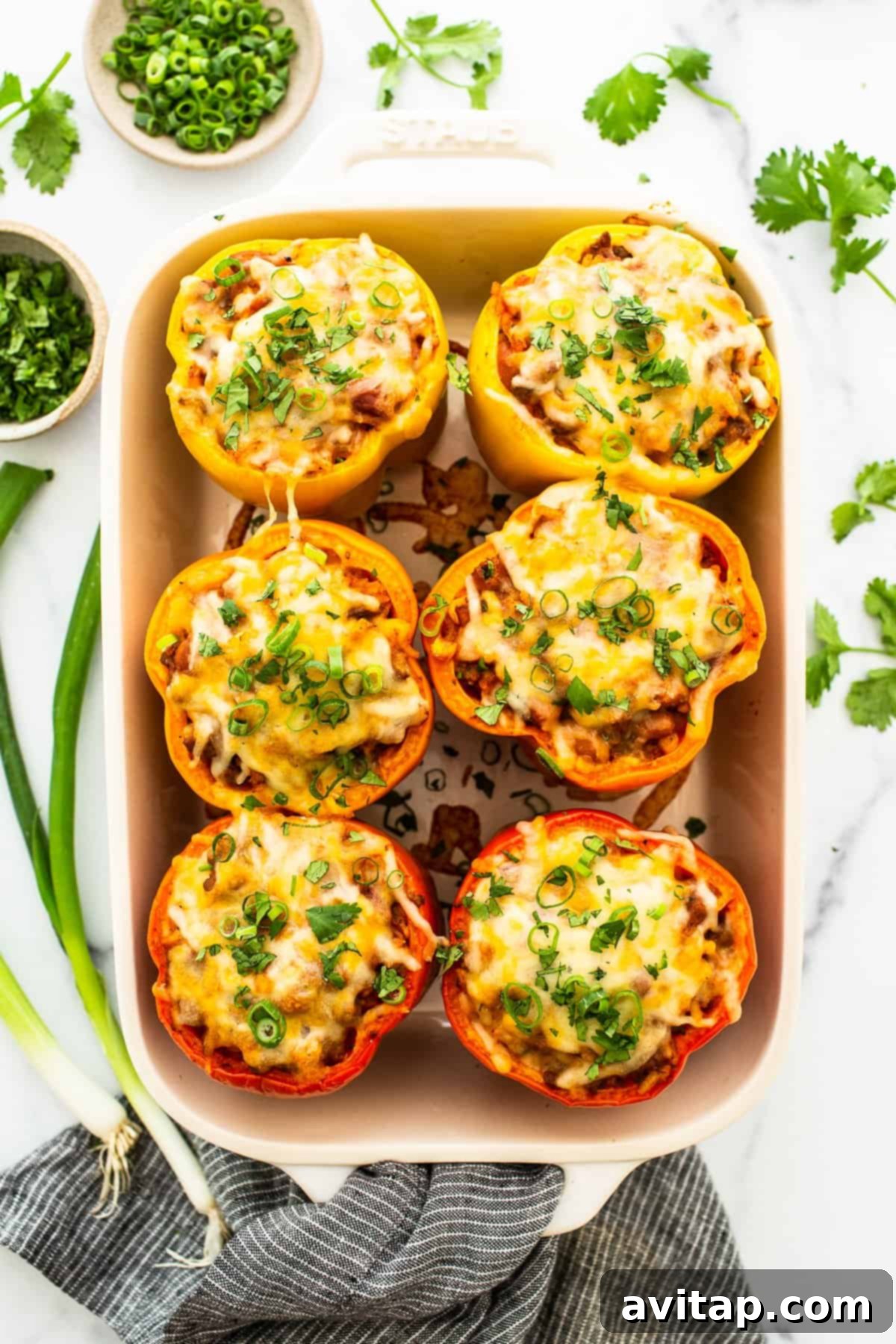Stuffed peppers in a casserole dish topped with green onion.