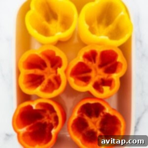 Sliced red and yellow peppers in a white baking dish.