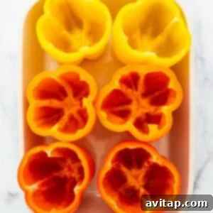 Sliced red and yellow peppers in a white baking dish.