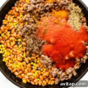 A skillet filled with ground beef, beans and tomatoes.