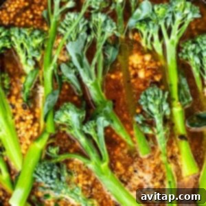 Broccolini cooking in a pan with broth on the stove.