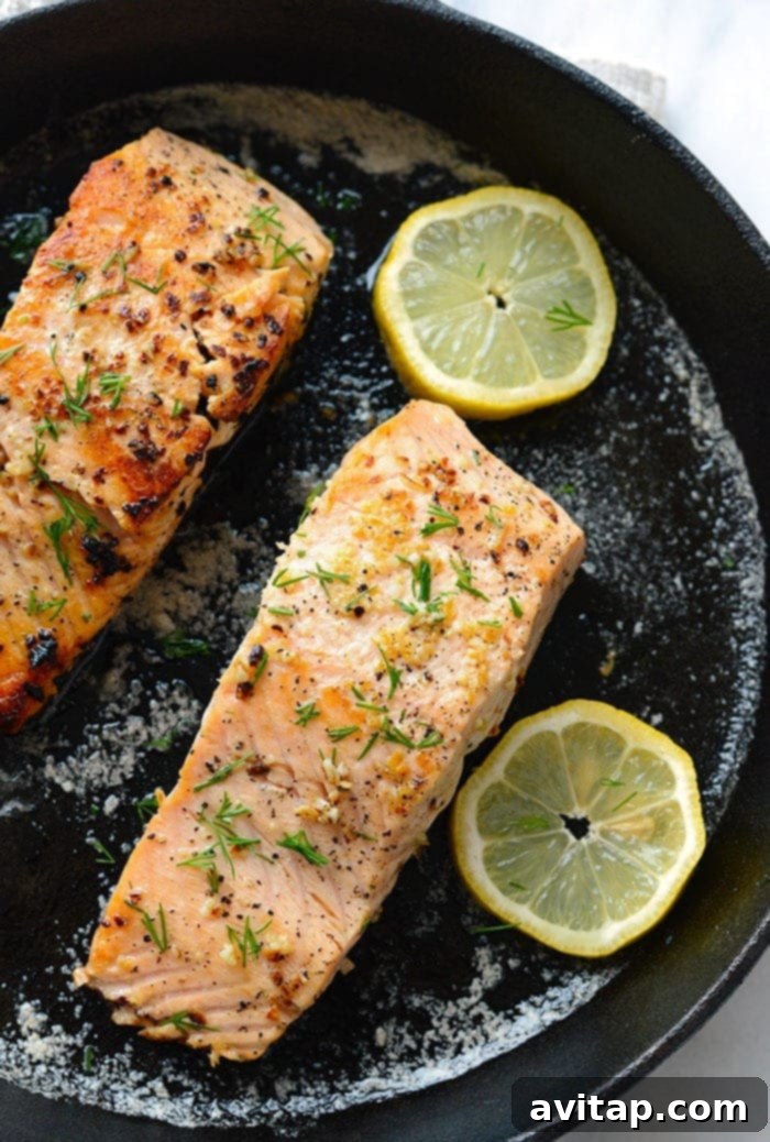 Make this Lemon Butter Pan Seared Salmon in 30 minutes or less using fresh salmon, butter, garlic, and lemon! A pan-seared salmon fillet with lemon slices in a cast iron pan.