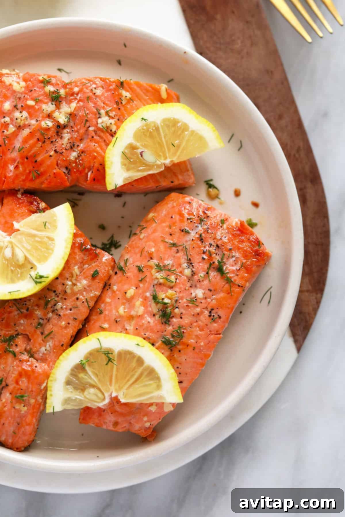 Make this Lemon Butter Pan Seared Salmon in 30 minutes or less using fresh salmon, butter, garlic, and lemon! Two seared salmon fillets on a plate with fresh lemon wedges.