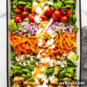 The Ultimate Garden Salad in a serving dish, beautifully adorned with homemade croutons, blue cheese crumbles, and a generous drizzle of both blue cheese and French dressings.