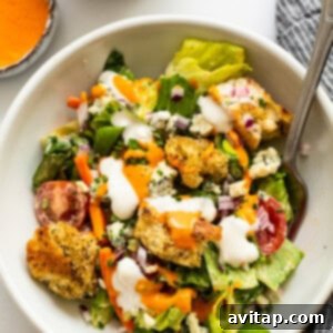 A white bowl showcasing a perfectly tossed garden salad with dressing, ready to be enjoyed.