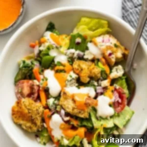 A perfectly dressed Ultimate Garden Salad in a white bowl, ready to be served and enjoyed, with a fork invitingly placed.