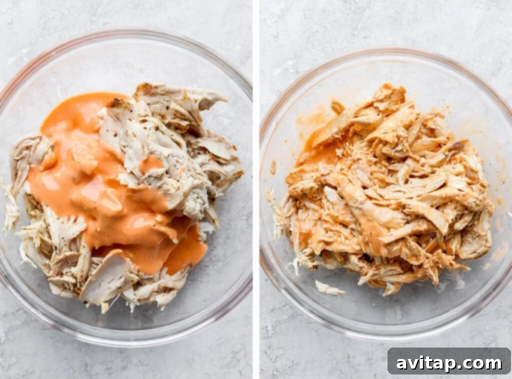 Shredded chicken being expertly tossed with a rich, creamy buffalo sauce in a large bowl, ensuring every piece is coated for maximum flavor.