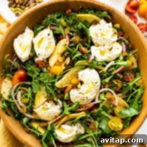 Apple burrata salad topped with torn burrata cheese, ready for serving.