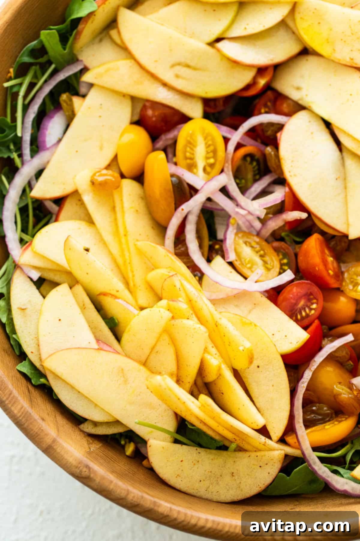 A vibrant Apple Burrata Salad with an array of fresh ingredients, artfully arranged in a bowl.
