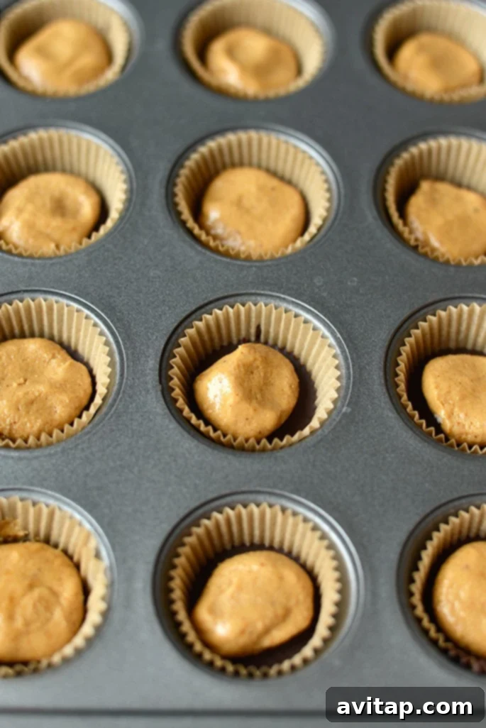 Peanut butter cups set in a mini muffin tin, ready to be frozen.