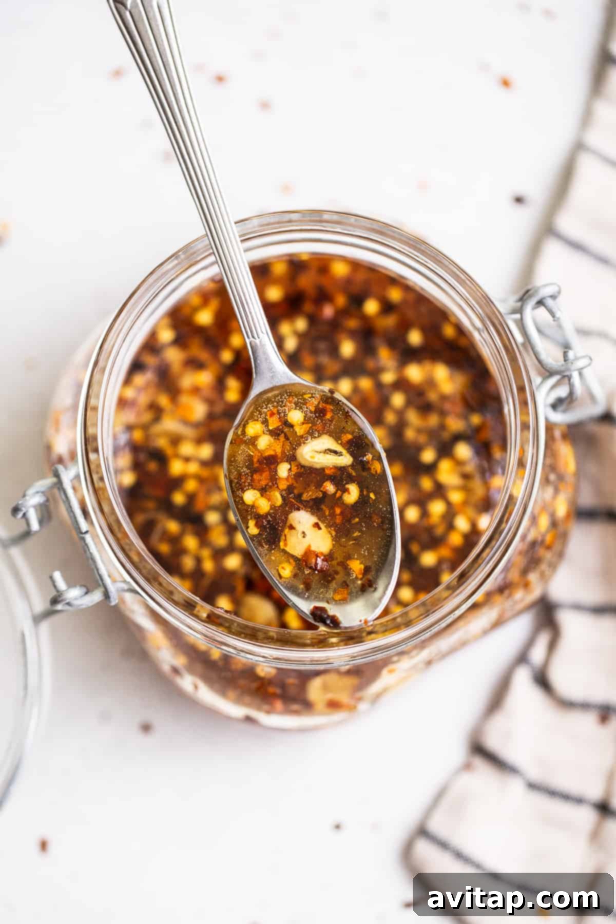 A close-up of the rich, amber homemade hot honey sauce in a clear glass jar, showing its glossy texture.