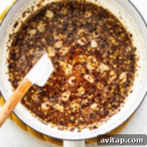 Hot honey ingredients simmering in a small pan, infusing flavors for the sauce.