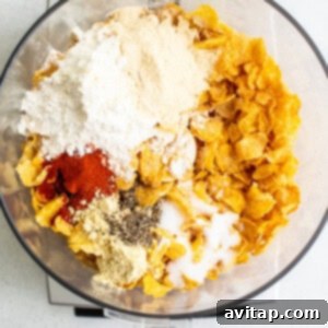 Processed cornflake topping with spices in a food processor, creating the chicken breading.