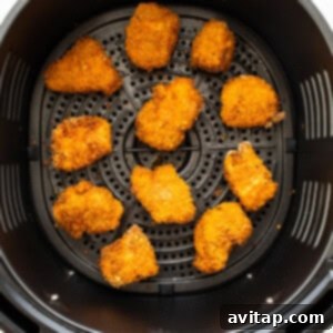 Crispy chicken pieces air frying in a basket, turning golden brown and perfectly cooked.
