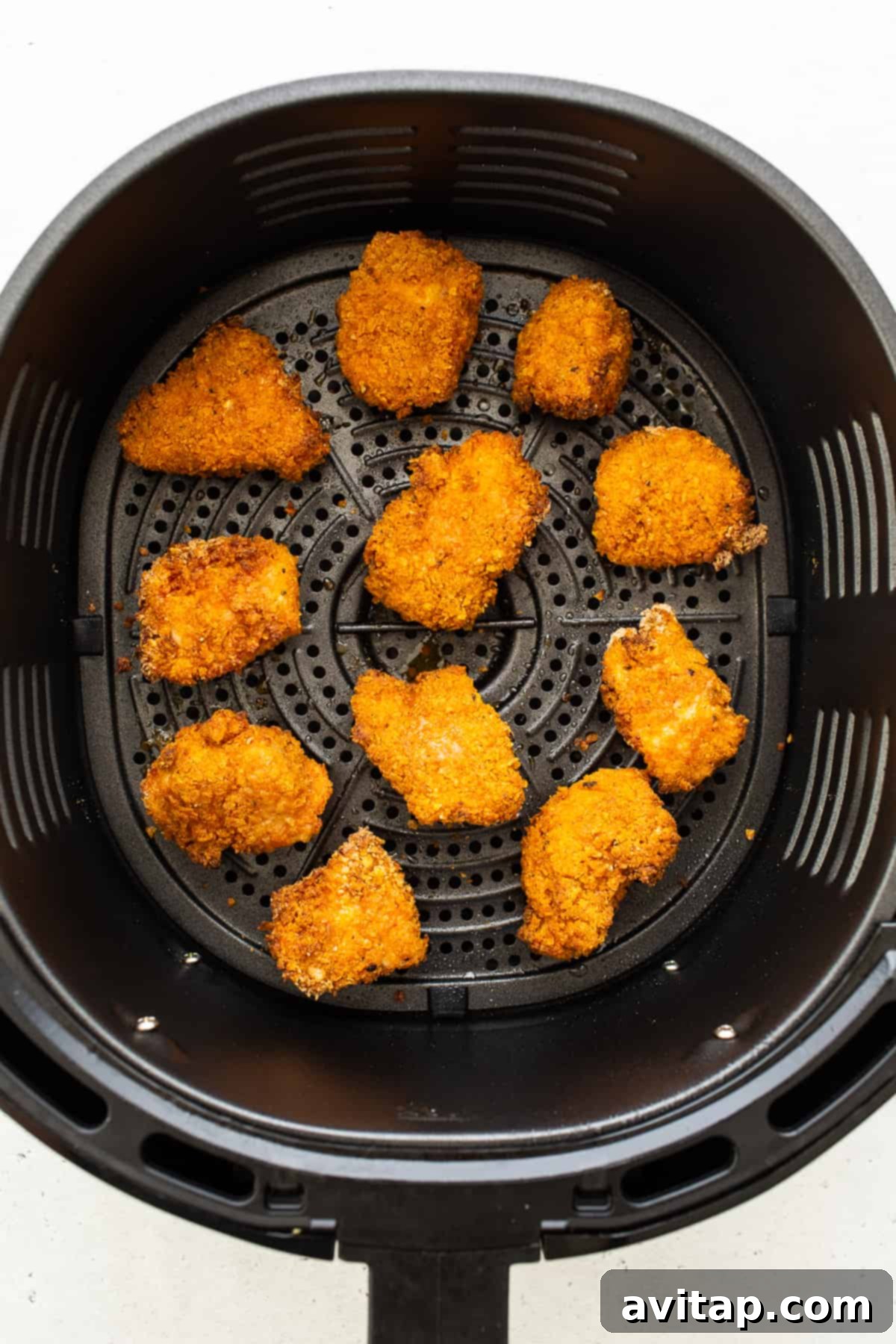 Golden brown, crispy chicken pieces cooking evenly in an air fryer basket, showcasing the healthy frying process.
