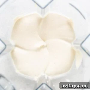 Effortless Vegan Cheesecake Bars 11 Creamy vegan cheesecake filling in a blender after the addition of melted coconut oil, ready for final blending.